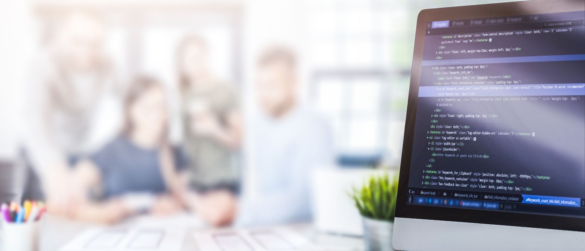 datenschutzmanagement-dqs-rechts im vordergrund ein monitor mit quellcode zeilen links im hintergrund verschwommen drei personen in einer arbeitssituation