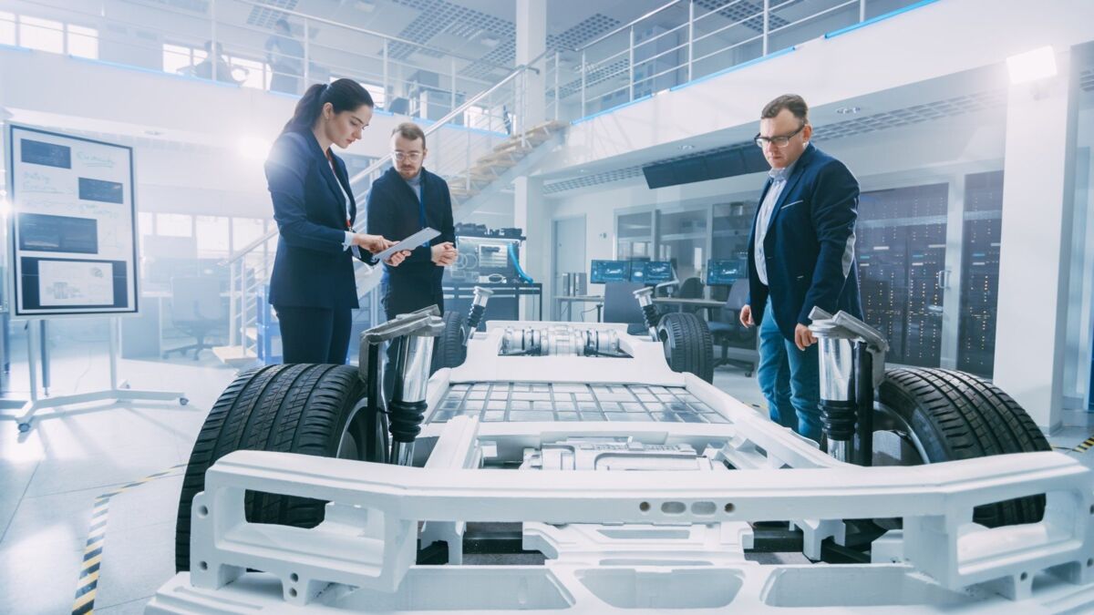 Automotive Design Engineers Talking while Working on Electric Car Chassis Prototype. In Innovation L