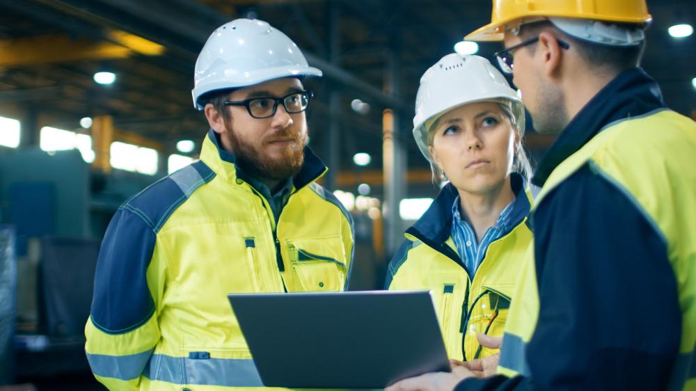 three people talking with high-visibility clothing and helmet